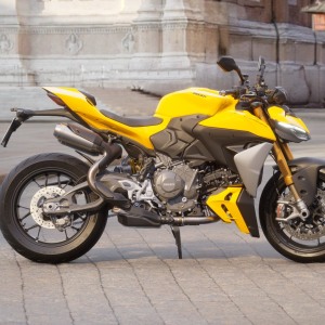 Yellow motorcycle on cobblestone street.